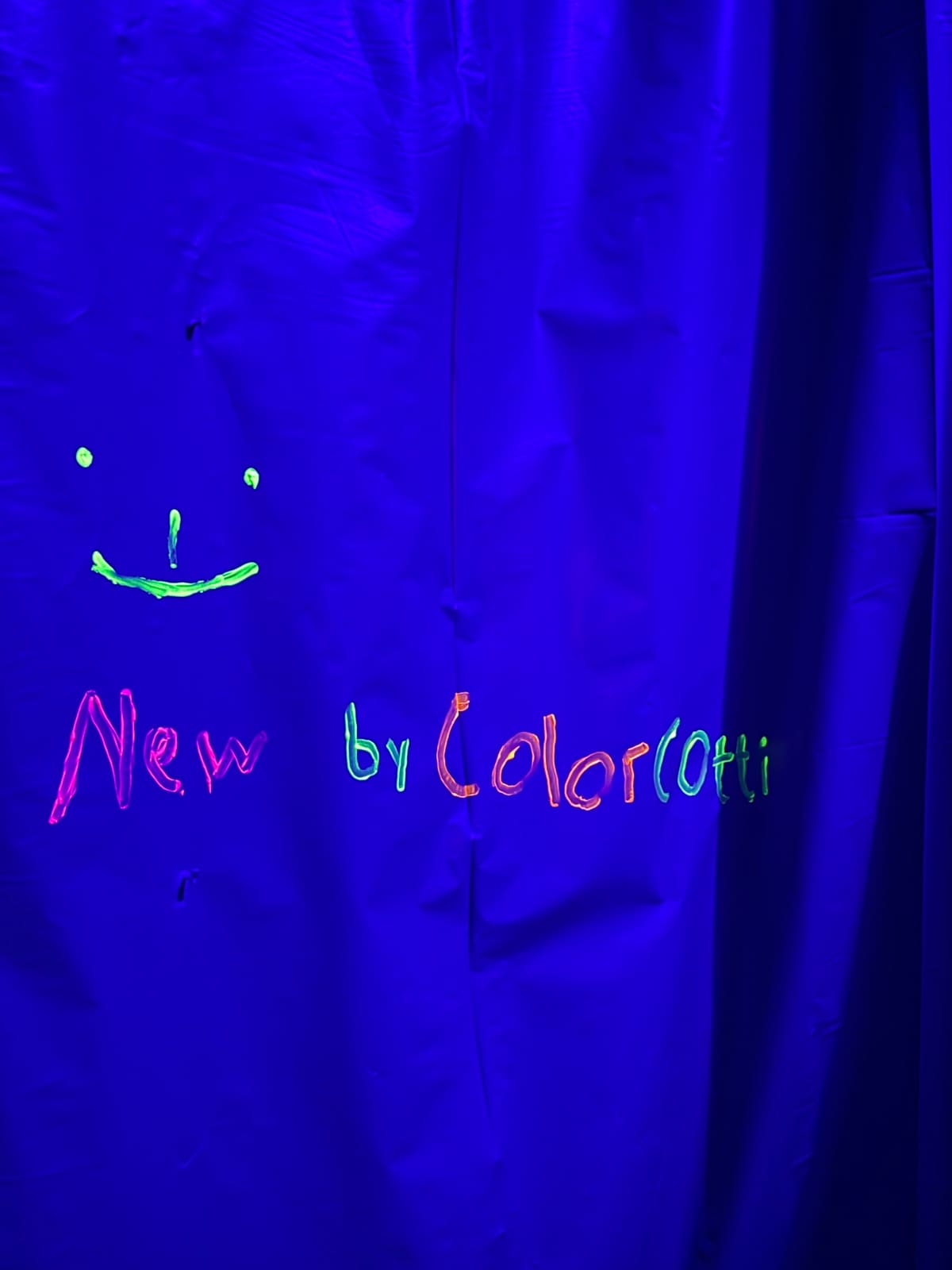 Leuchtender Schriftzug und Kunstwerk unter Schwarzlicht bei ColorCotti